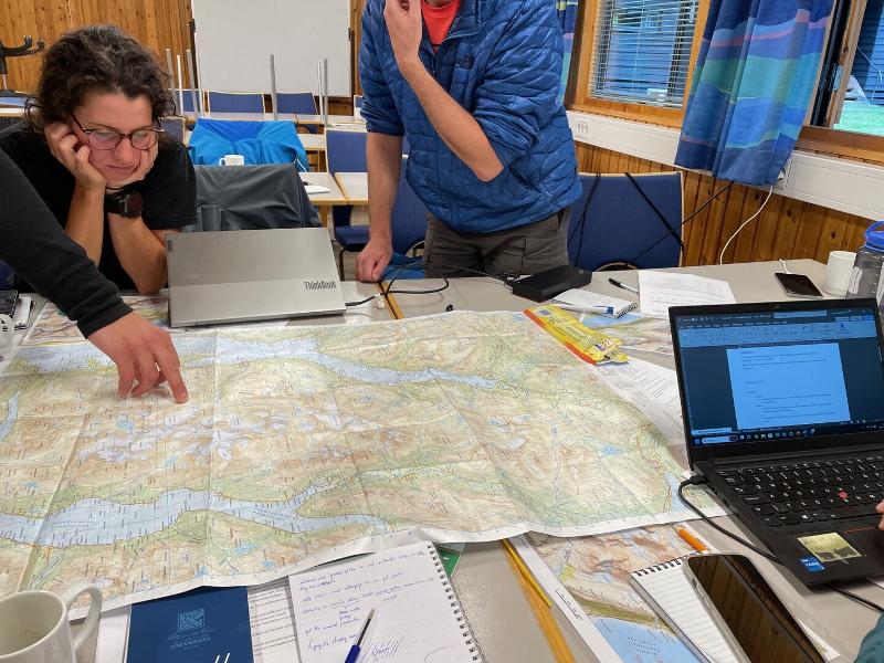 People standing over a table, before a map.